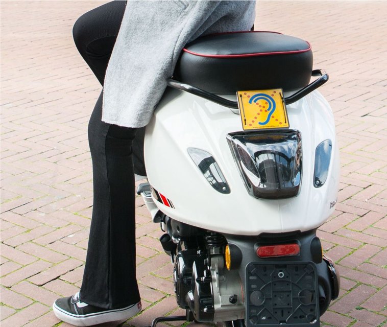 Limited Hearing reflecterend waarschuwingsbordje op witte scooter voor duidelijkheid in het verkeer Limited Hearing reflecterend waarschuwingsbordje op witte scooter voor duidelijkheid in het verkeer