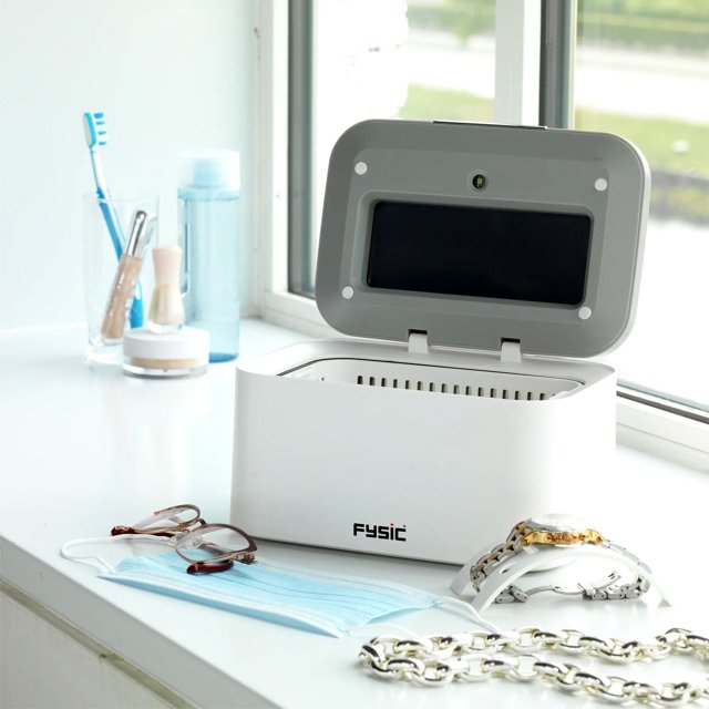Fysic FC-35 reiniger in gebruik op vensterbank met bril, mondkapje en sieraden Fysic FC-35 reiniger in gebruik op vensterbank met bril, mondkapje en sieraden