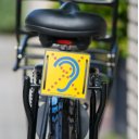 Limited Hearing reflecterend bordje op fietsbagagedrager met geel waarschuwingsteken voor slechthorenden Limited Hearing reflecterend bordje op fietsbagagedrager met geel waarschuwingsteken voor slechthorenden