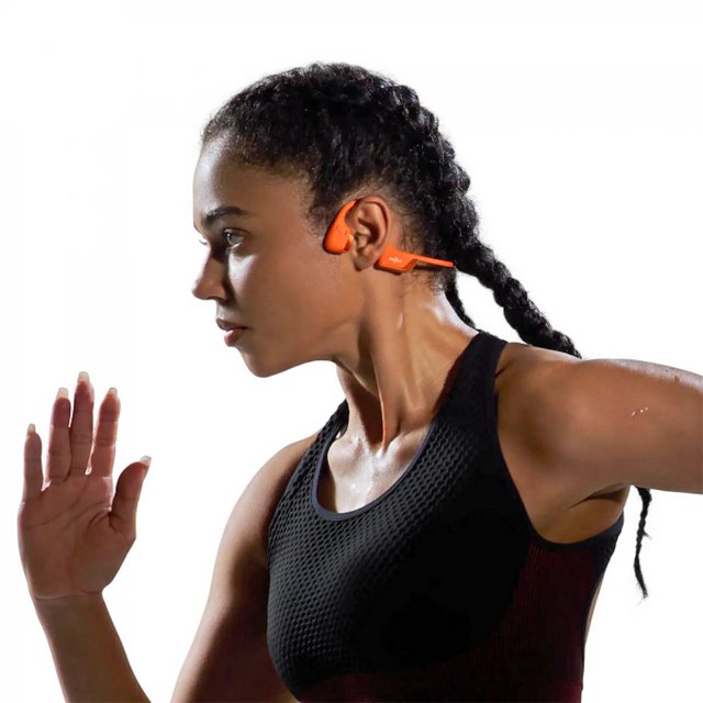 Vrouw in zwarte sportkleding draagt de Shokz OpenRun Pro 2 Mini hoofdtelefoon in oranje tijdens een intensieve hardloopsessie – HearPlanet Vrouw in zwarte sportkleding draagt de Shokz OpenRun Pro 2 Mini hoofdtelefoon in oranje tijdens een intensieve hardloopsessie – HearPlanet