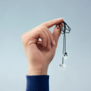 Hand houdt Alpine oordoppen met zwart verbindingskoord voor gehoorbescherming tegen verlies Hand houdt Alpine oordoppen met zwart verbindingskoord voor gehoorbescherming tegen verlies