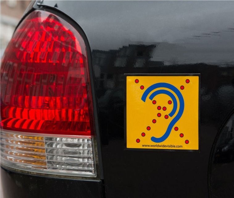 Limited Hearing reflecterende waarschuwingssticker op achterzijde van auto met geel en blauw oor symbool Limited Hearing reflecterende waarschuwingssticker op achterzijde van auto met geel en blauw oor symbool