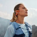 Vrouw geniet van muziek met de Shokz OpenRun Pro 2 oranje tijdens het hardlopen – bone conduction sportkoptelefoon – HearPlanet. Vrouw geniet van muziek met de Shokz OpenRun Pro 2 oranje tijdens het hardlopen – bone conduction sportkoptelefoon – HearPlanet.