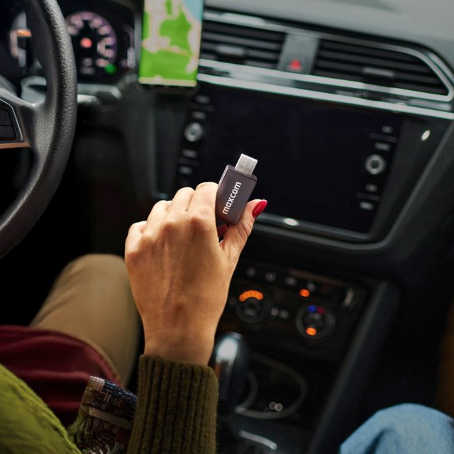 Persoon gebruikt Maxcom Wave MC02 adapter in een moderne auto Persoon gebruikt Maxcom Wave MC02 adapter in een moderne auto